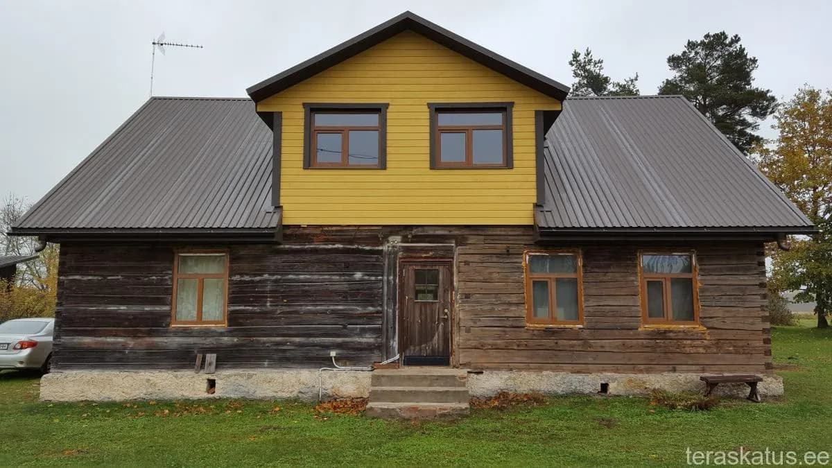 Tumepruun palkmaja erkkollase viilulisandiga ja uue halli profiilplekk-katusega mõlemal osal