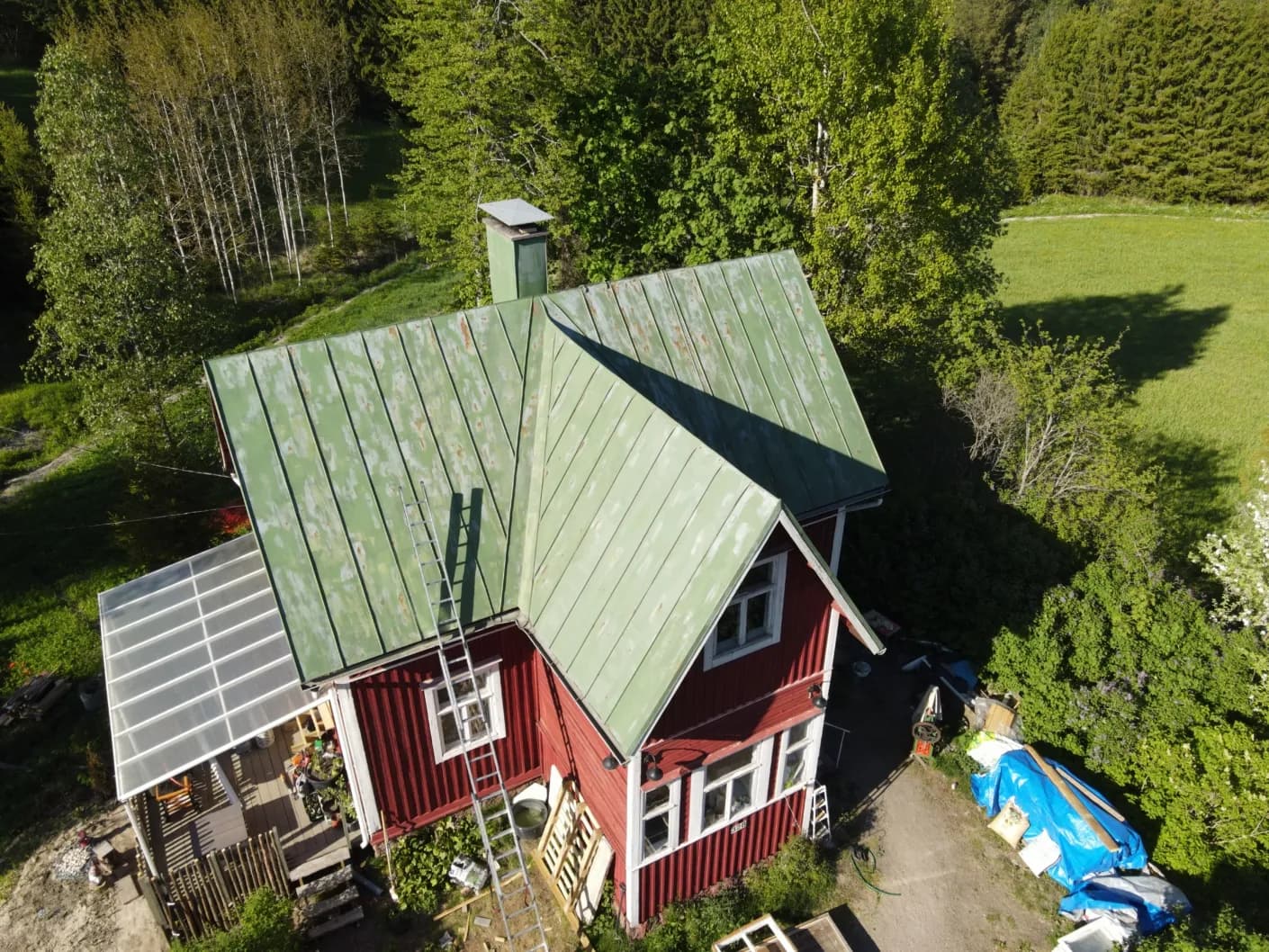 Aerofoto suvilast enne katuse värskendust, laiguline ja kulunud rohekashall plekk-katus, punane puitfassaad, männimets ümber