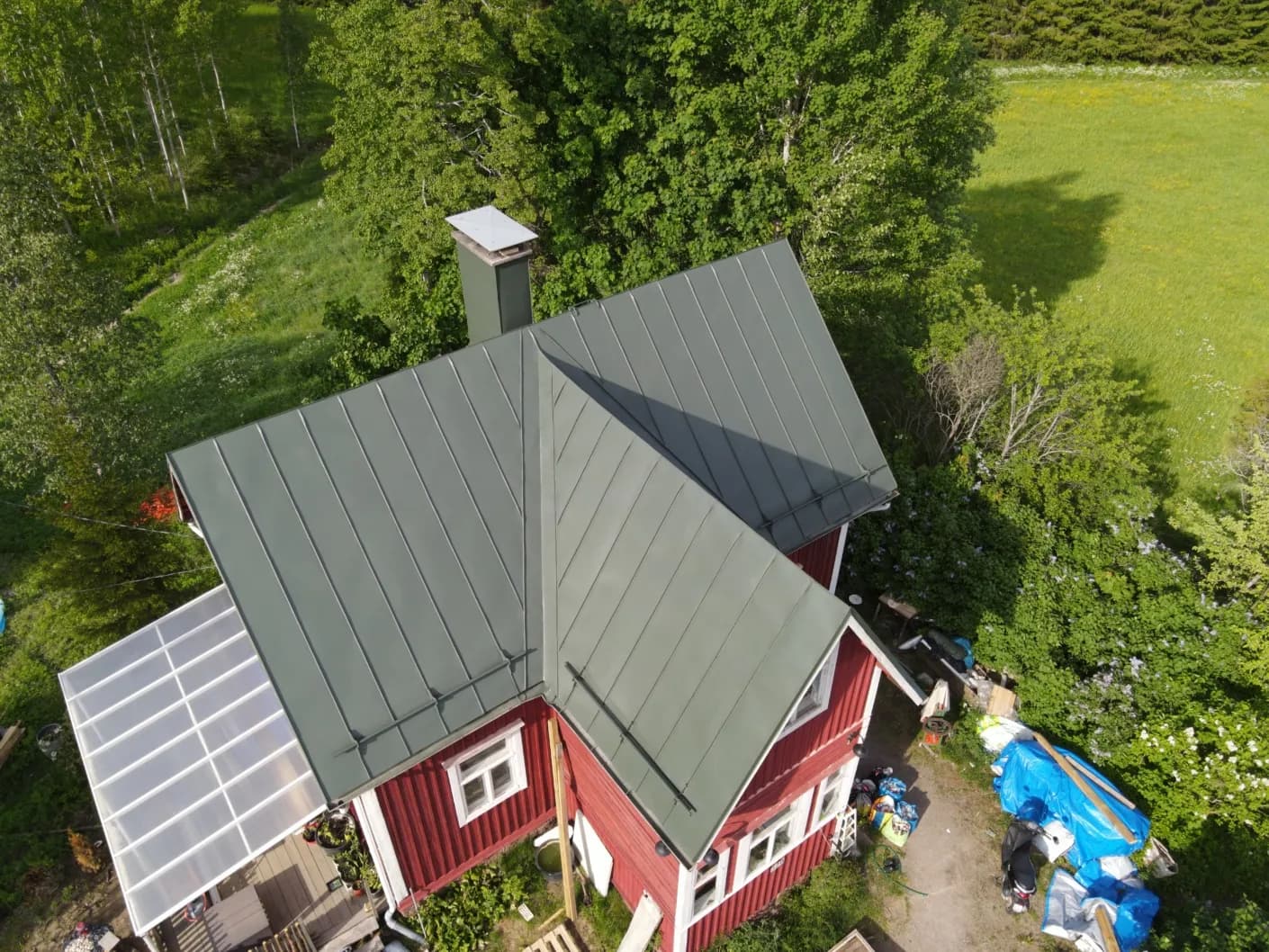 Sama suvila katus pärast värskendust, ühtlane rohekashall plekk-pind, sama punane puitfassaad ja männimets
